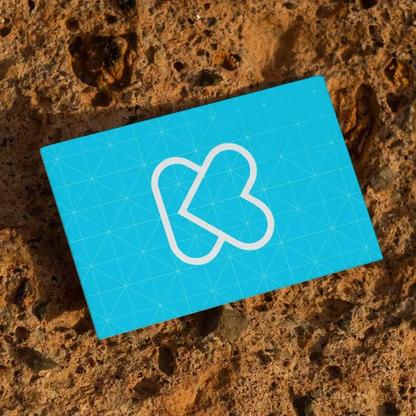 A blue card with a white geometric heart-shaped logo lies on a rough, brown textured surface.