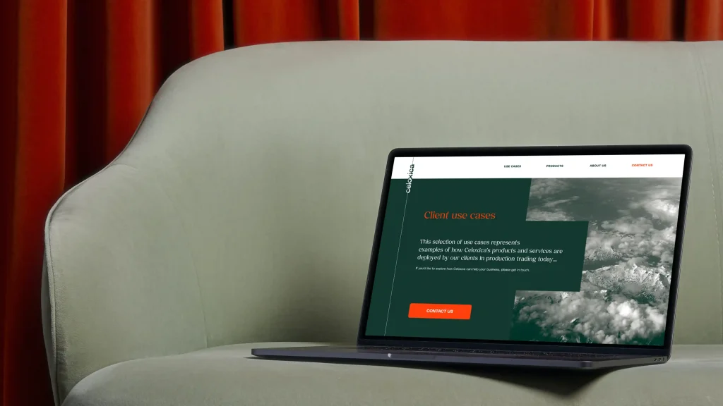 A laptop rests on a light green sofa in front of a red curtain, displaying a rebrand of the website’s Client use cases page, featuring images of clouds and a prominent orange Contact us button.